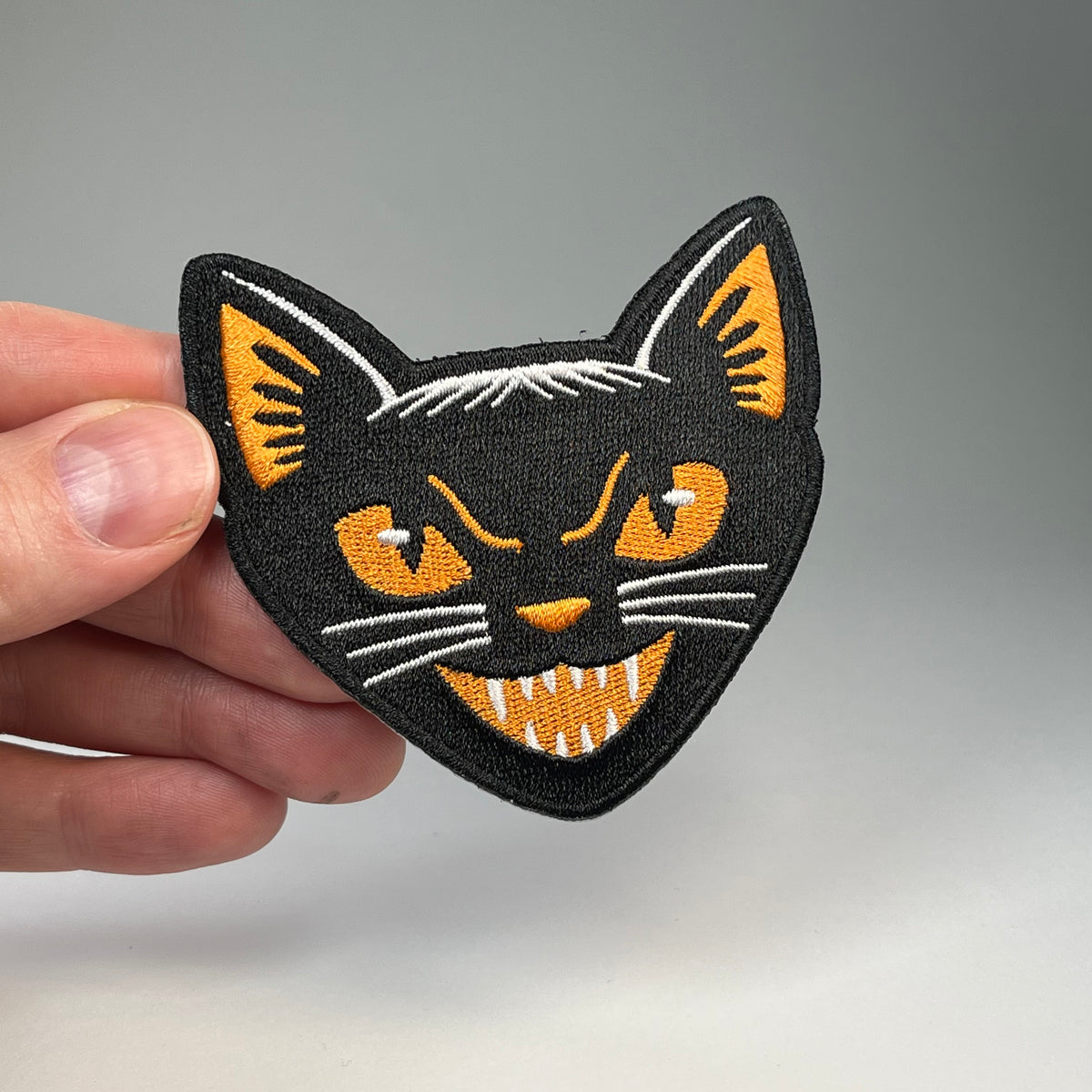 Hand holding the Black Cat vintage style Halloween embroidered patch