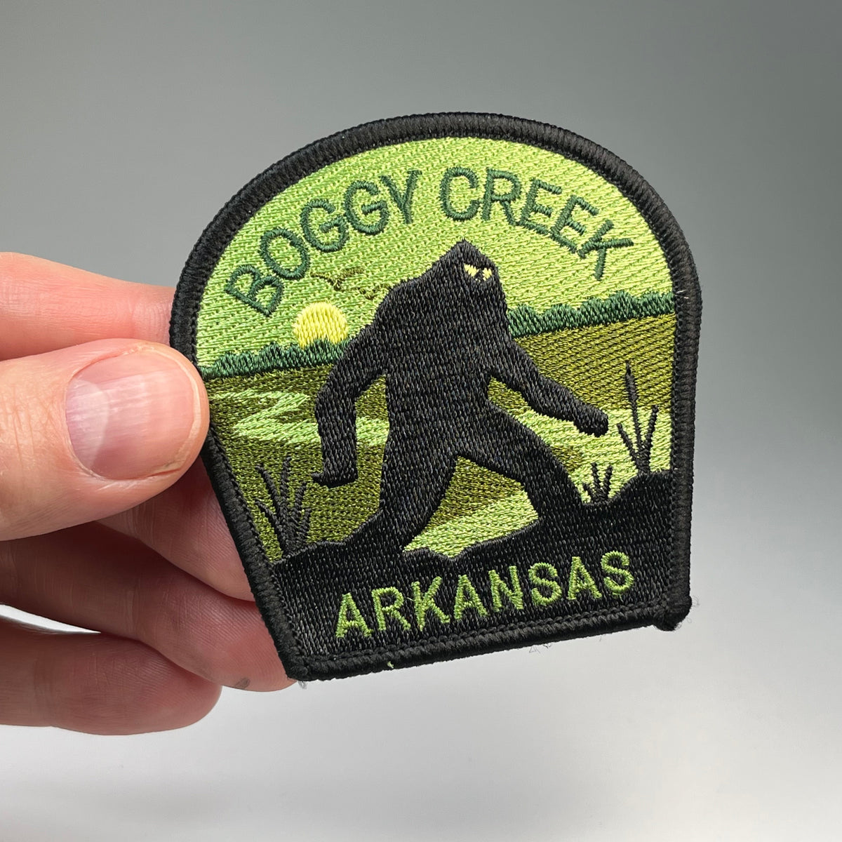 Hand holding the Boggy Creek Arkansas Monster cryptid travel patch