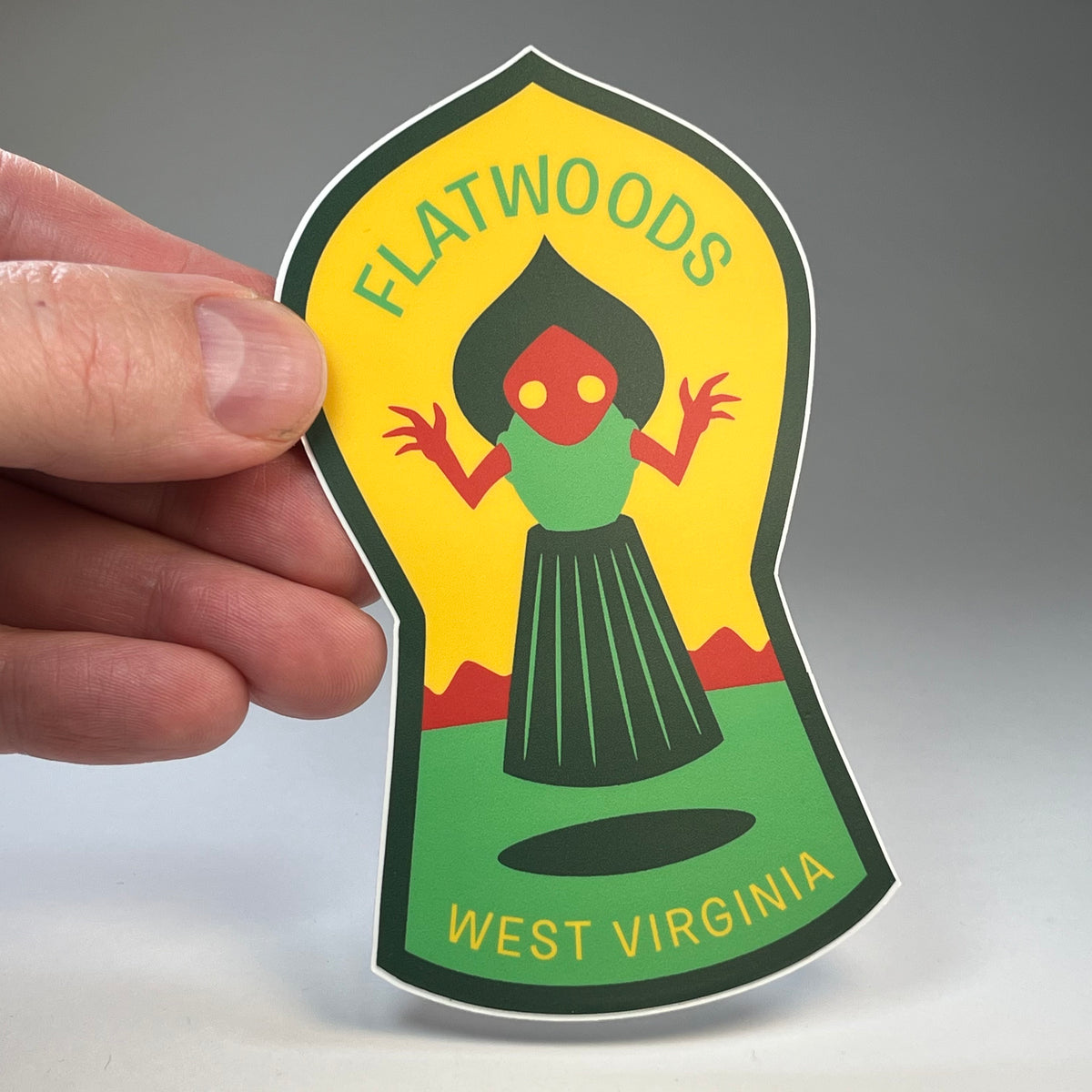 Hand holding the Flatwoods West Virginia Monster cryptid travel sticker