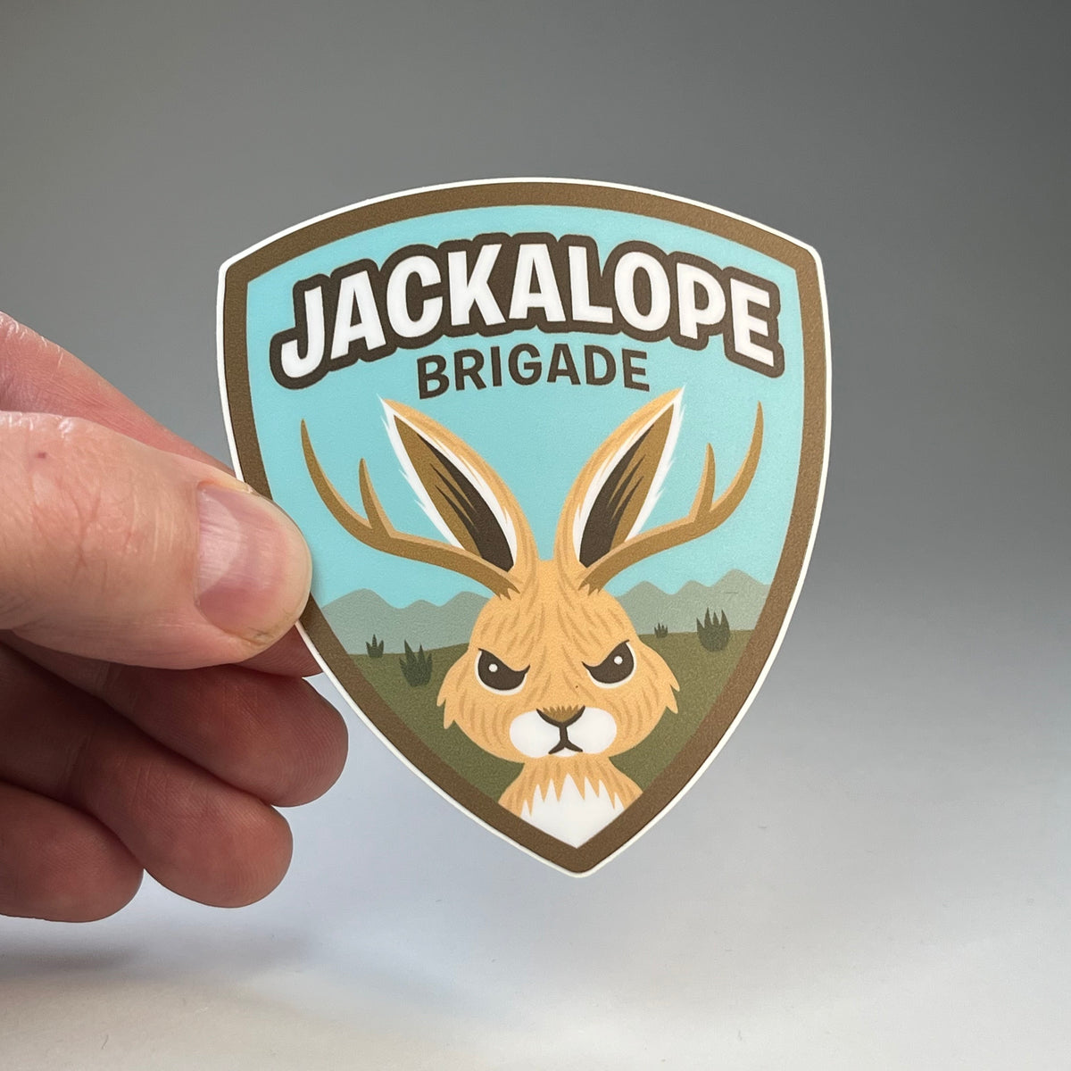 Hand holding the Jackalope Brigade cryptid sticker