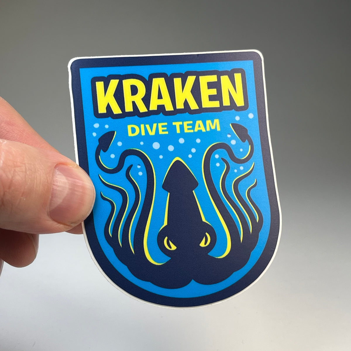 Hand holding the Kraken Dive Team cryptid military badge sticker