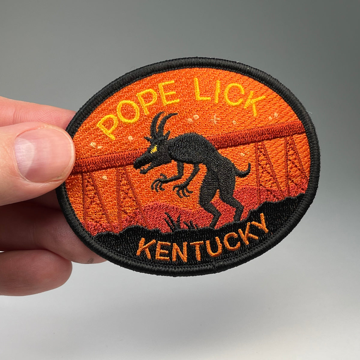Hand holding the Pope Lick Kentucky Goatman cryptid travel patch