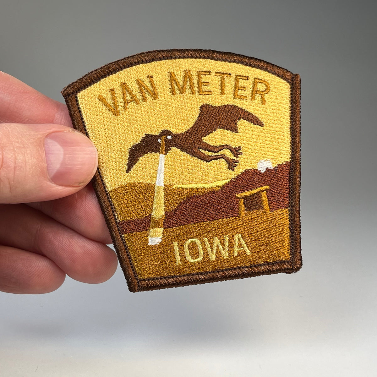 Hand holding the Van Meter Iowa Visitor cryptid travel patch