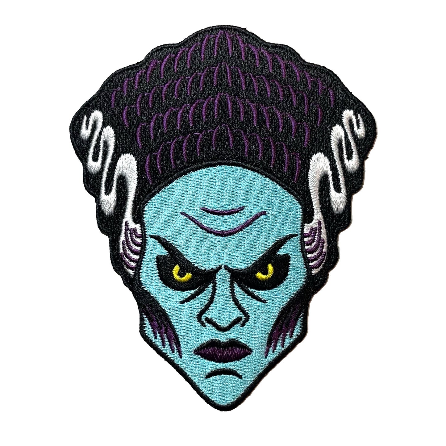 Embroidered patch of a blue-skinned Bride Of Frankenstein with yellow eyes on a white background.