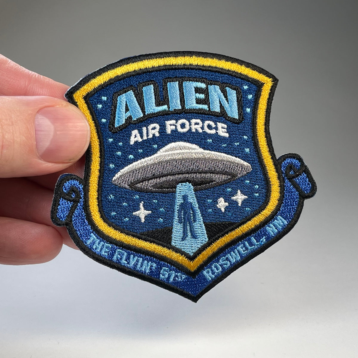 Hand holding the Alien Air Force cryptid military badge embroidered patch