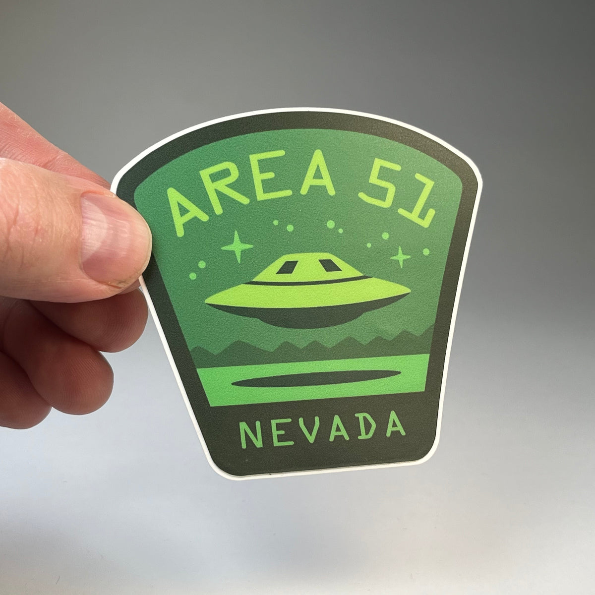 Hand holding the Area 51 Nevada UFO travel sticker