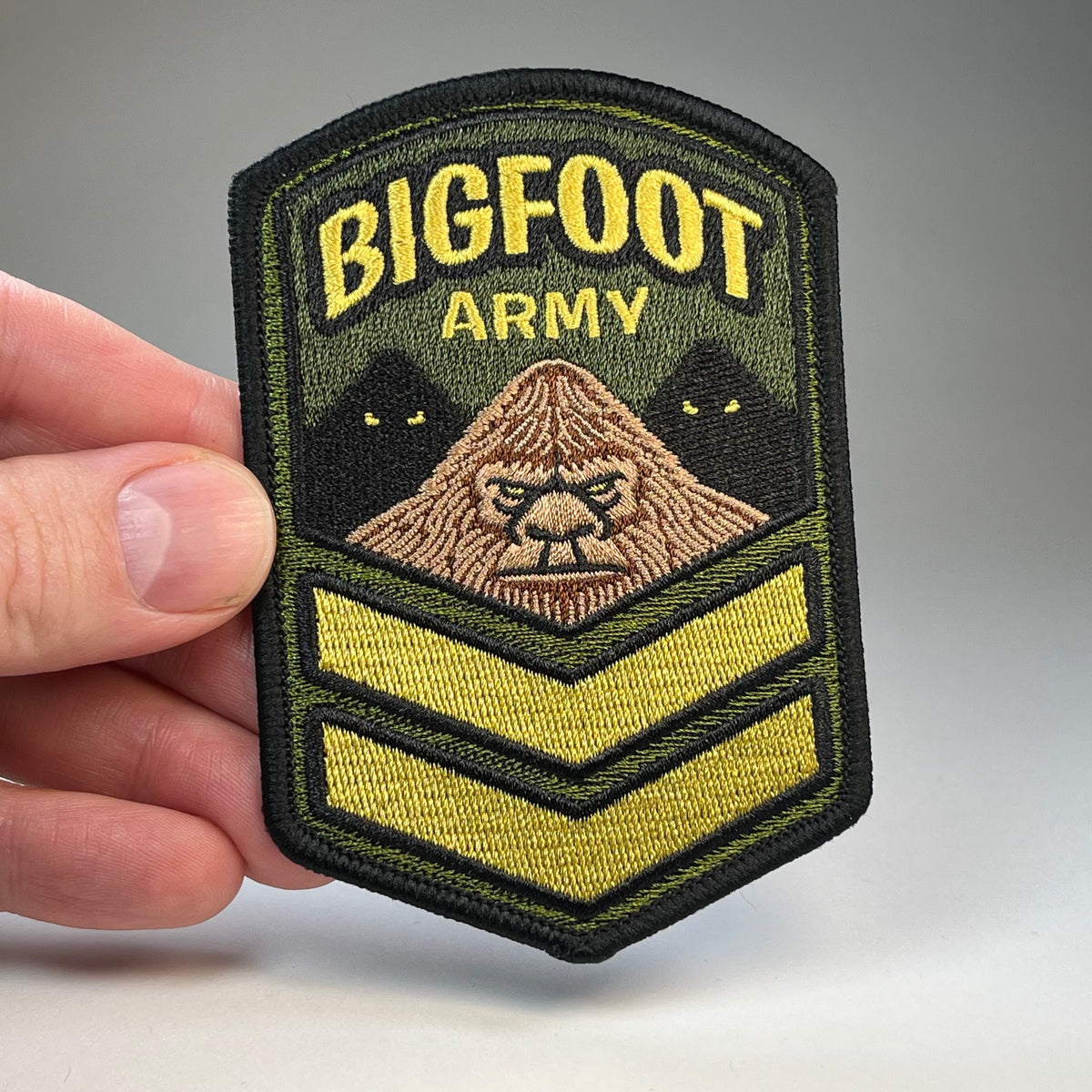 Hand holding the Bigfoot Army cryptid military badge embroidered patch