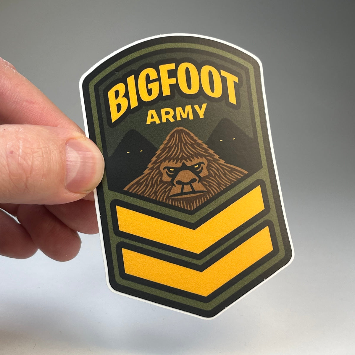 Hand holding the Bigfoot Army cryptid military badge sticker