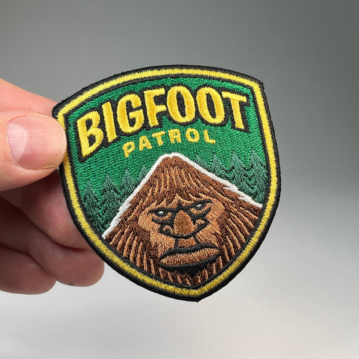 Hand holding the Bigfoot Patrol cryptid military badge embroidered patch