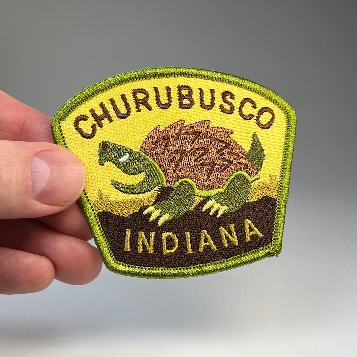 Hand holding the Churubusco Indiana Turtle cryptid travel patch