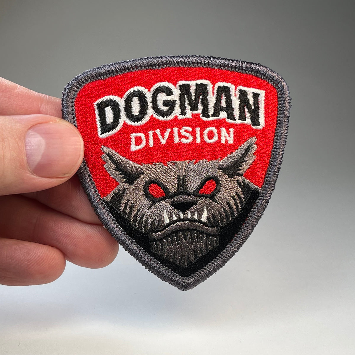 Hand holding the Dogman Division cryptid military badge embroidered patch