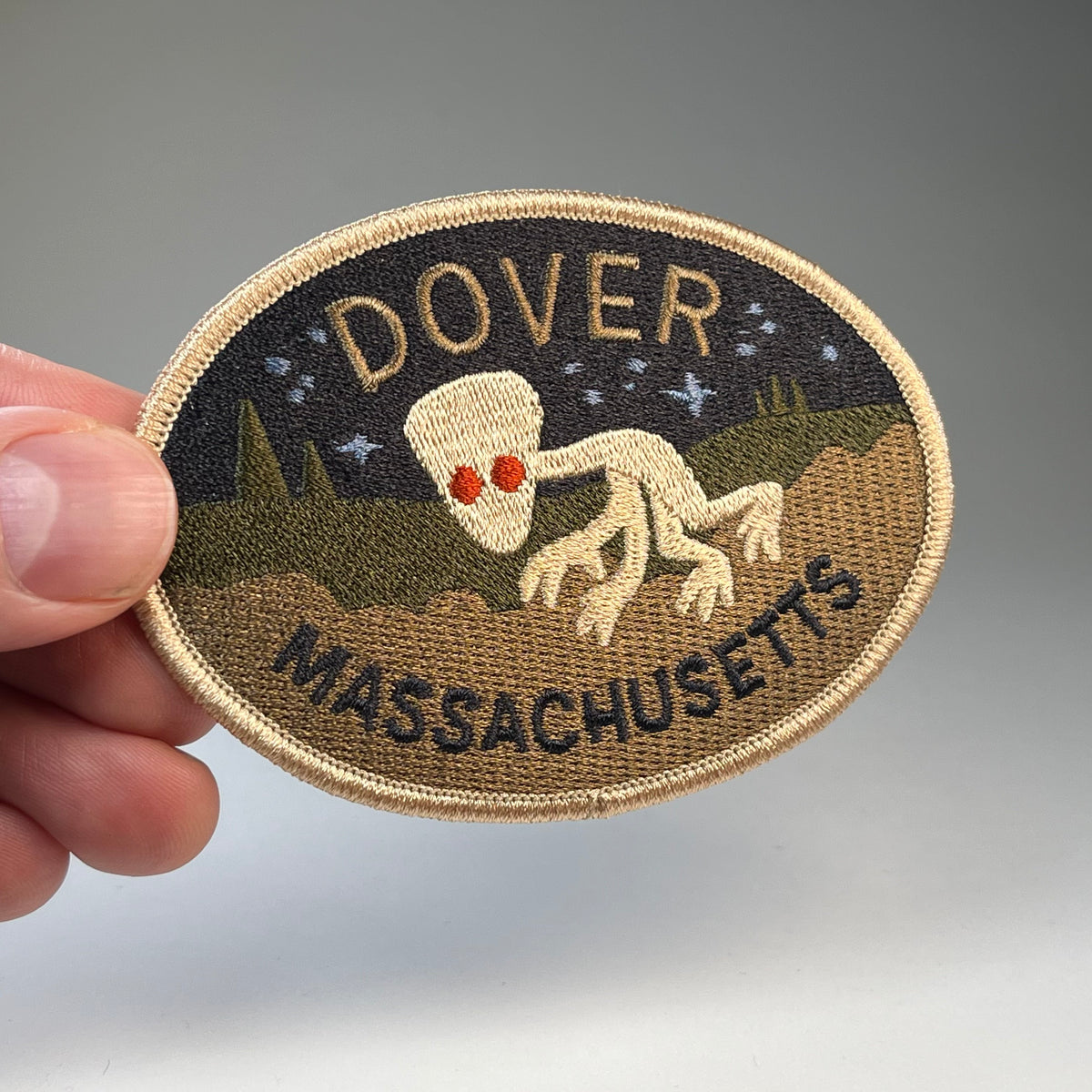 Hand holding the Dover Massachusetts Demon cryptid travel patch