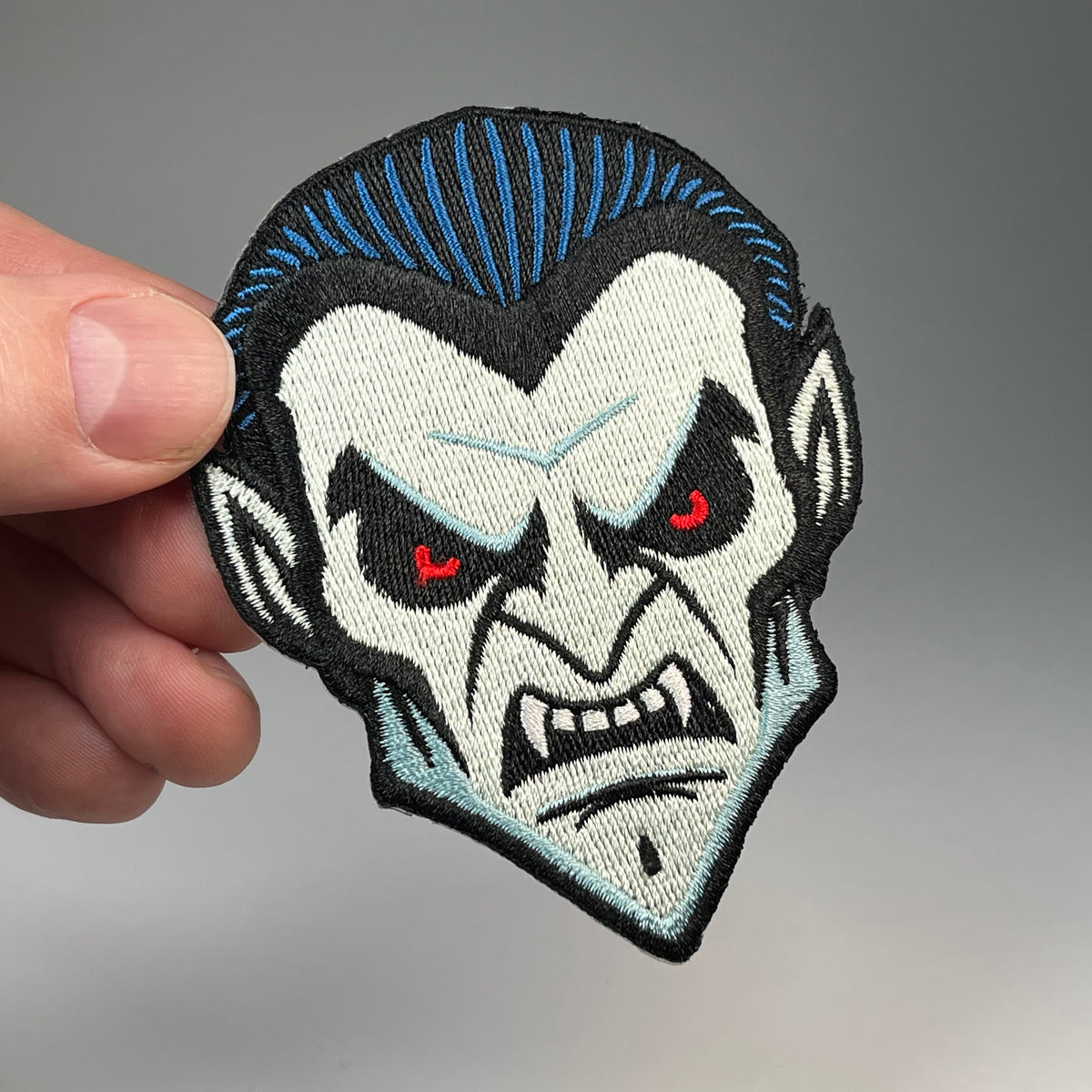 Hand holding the Dracula head embroidered patch