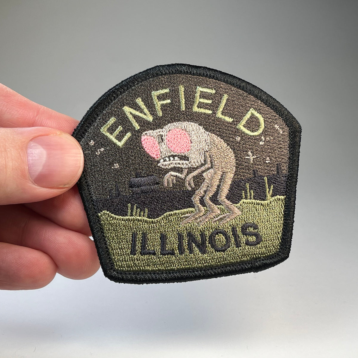 Hand holding the Enfield Illinois Horror cryptid travel patch