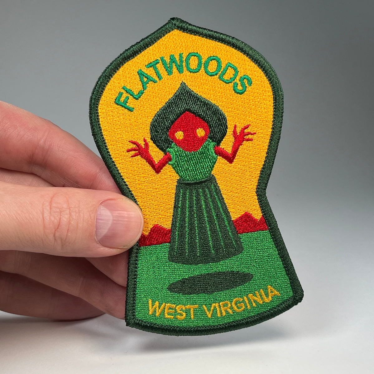 Hand holding the Flatwoods West Virginia Monster cryptid travel patch
