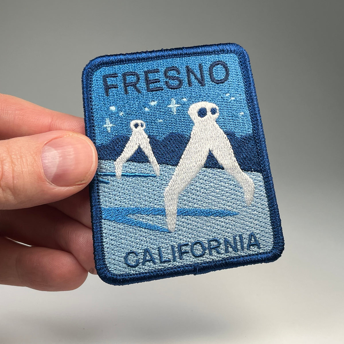 Hand holding the Fresno California Nightcrawlers cryptid travel patch