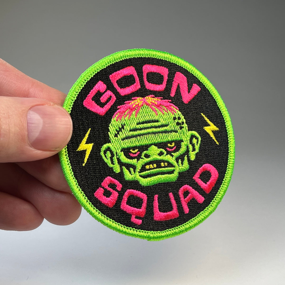 Hand holding the Goon Squad cryptid military badge embroidered patch
