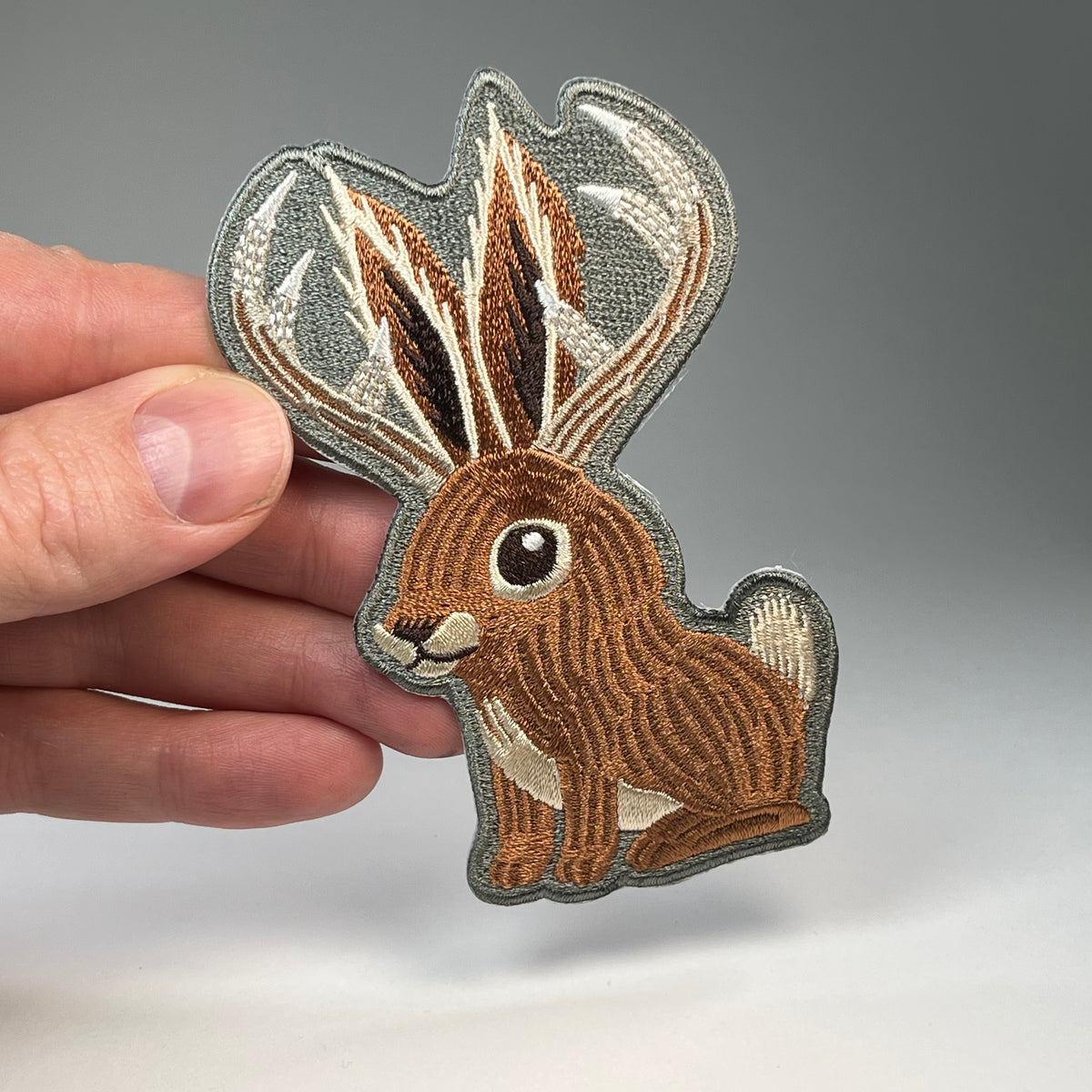 Hand holding the Jackalope Cute cryptid embroidered patch