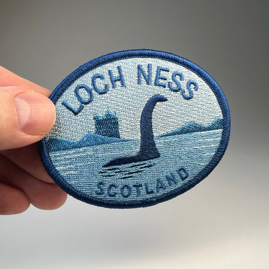 Hand holding the Loch Ness Scotland Nessie cryptid travel patch