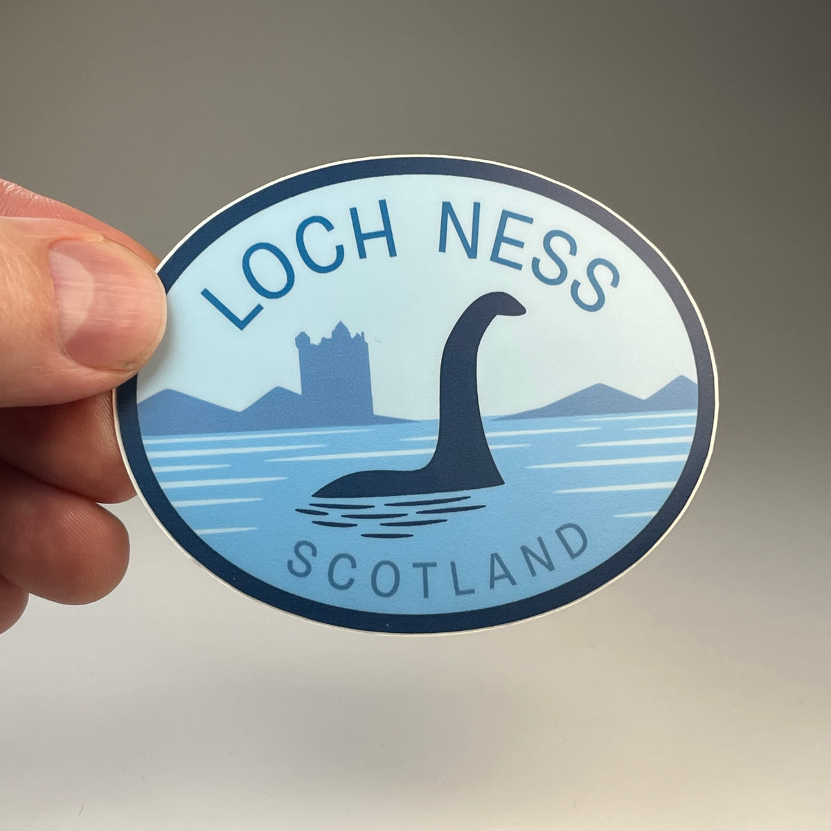 Hand holding the Loch Ness Scotland Nessie cryptid travel sticker