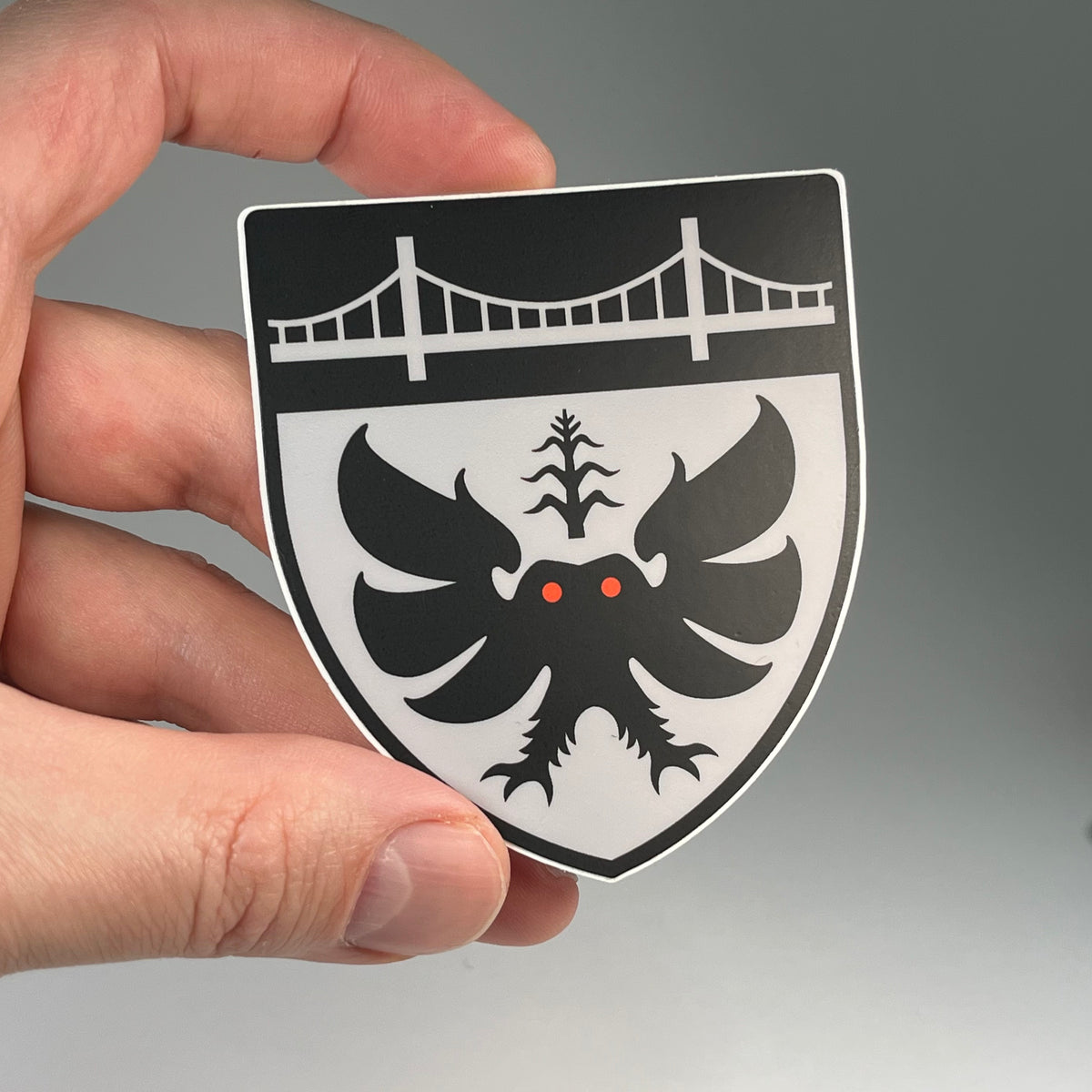 Hand holding the Mothman Heraldic cryptid sticker