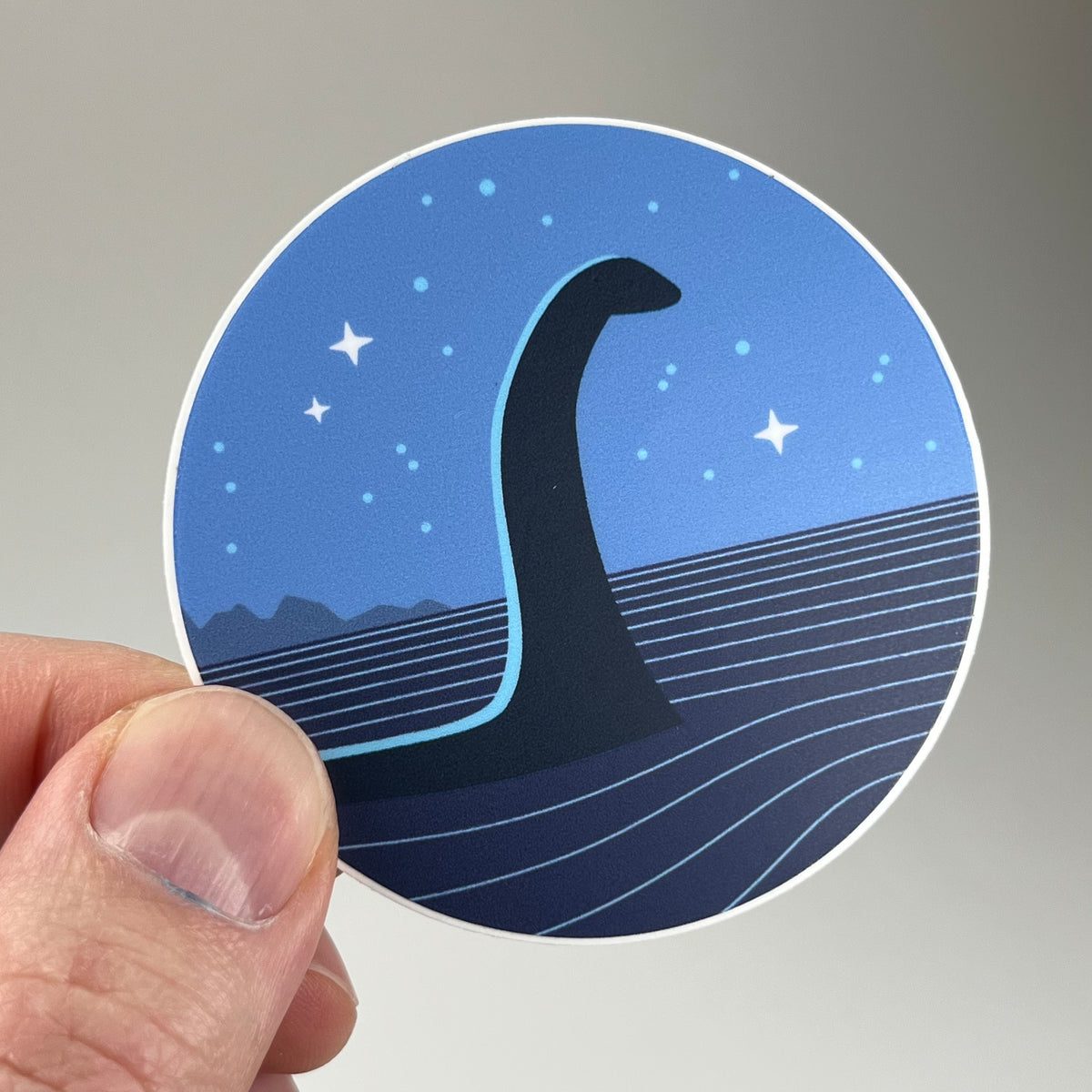 Hand holding the Nessie Minimalist Circle Sticker