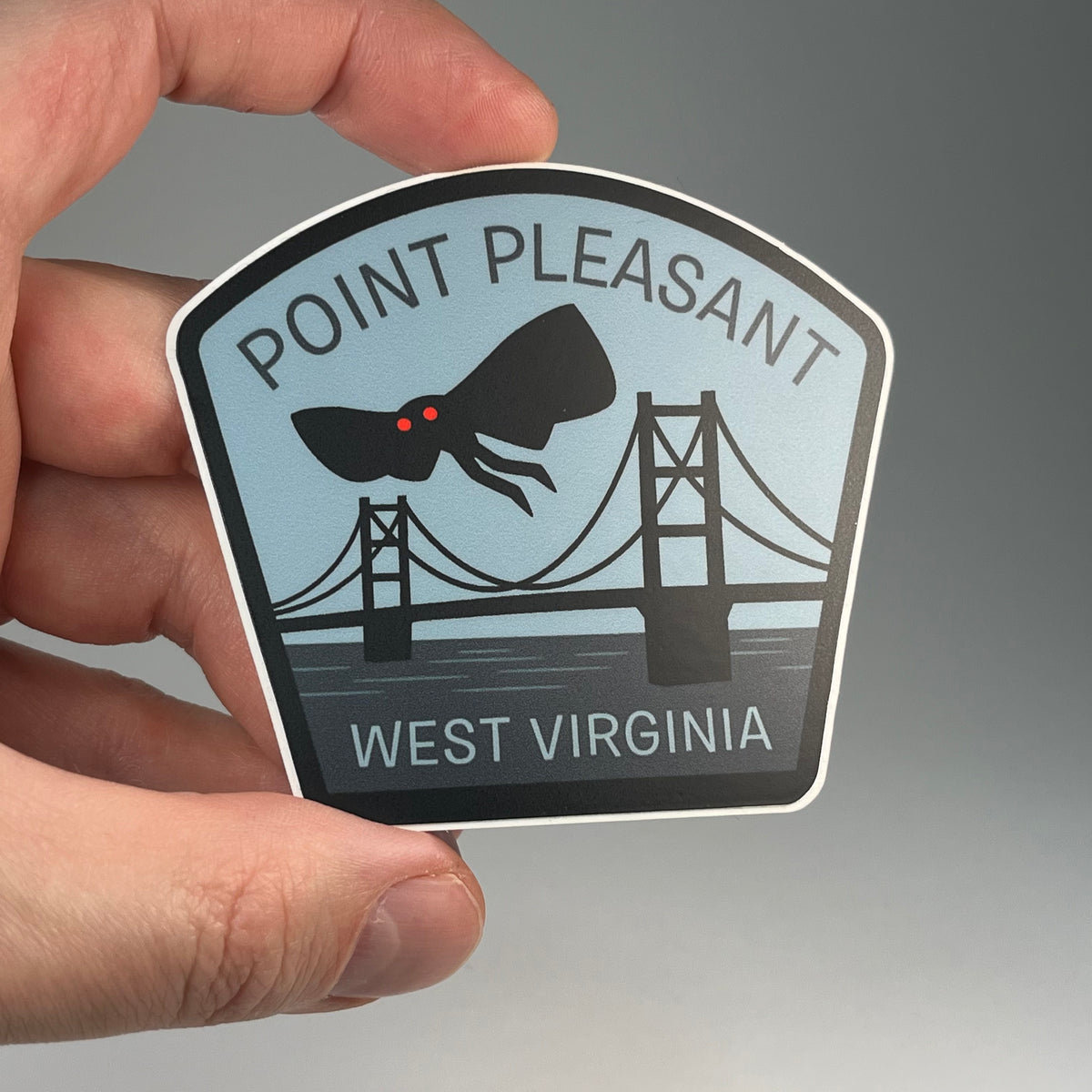 Hand holding the Point Pleasant West Virginia Mothman cryptid travel sticker