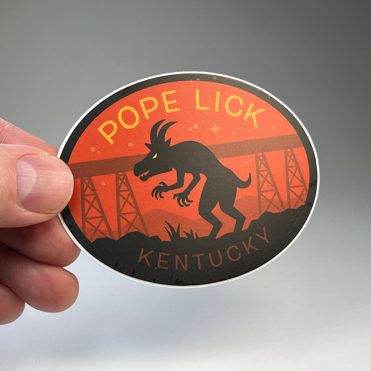 Hand holding the Pope Lick Kentucky Goatman cryptid travel sticker