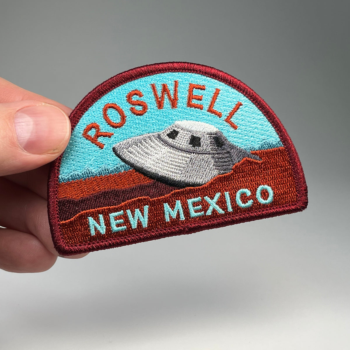 Hand holding the Roswell New Mexico UFO travel patch
