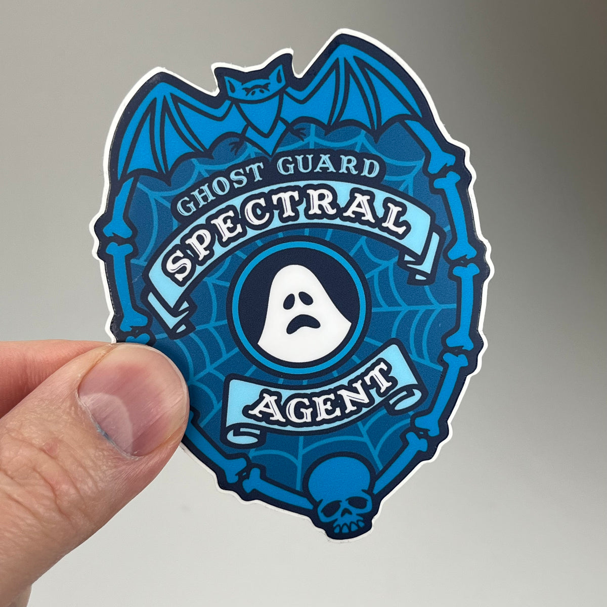 Hand holding the Spectral Agent Police Badge Ghost Sticker